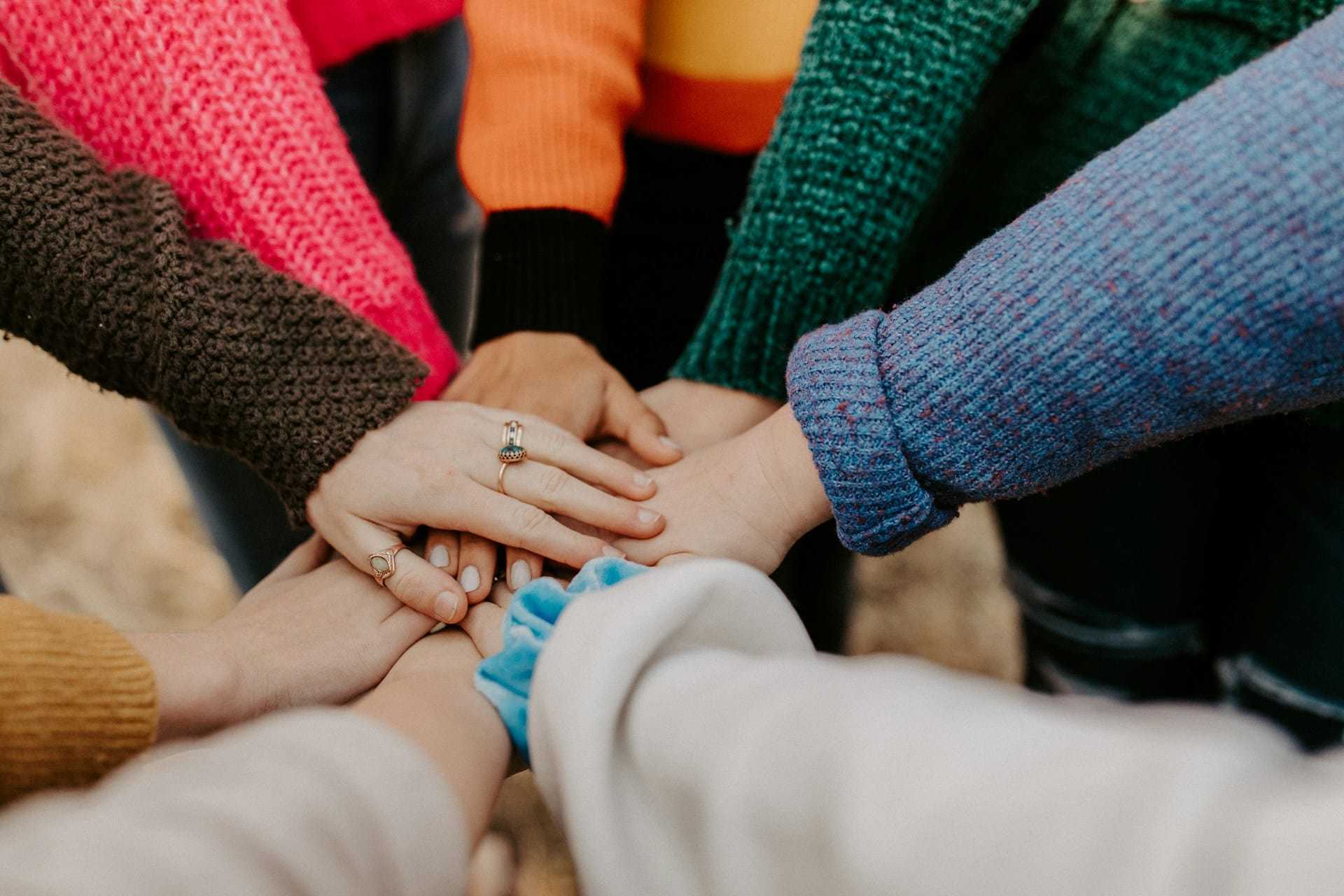 A group of diverse people joining hands in a circle, symbolizing unity and teamwork.